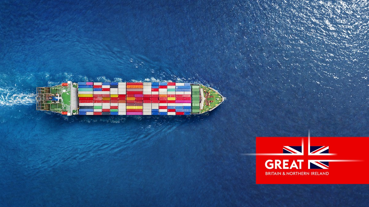 A cargo ship at sea, heavily laden with shipping containers with a logo for Great campaign on the right