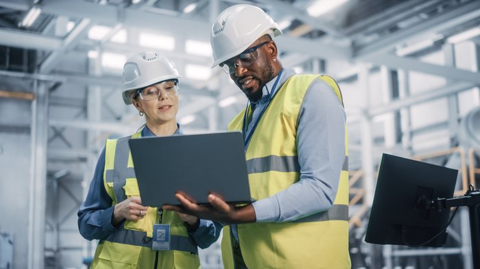 Woman and man look at laptop on construction site
